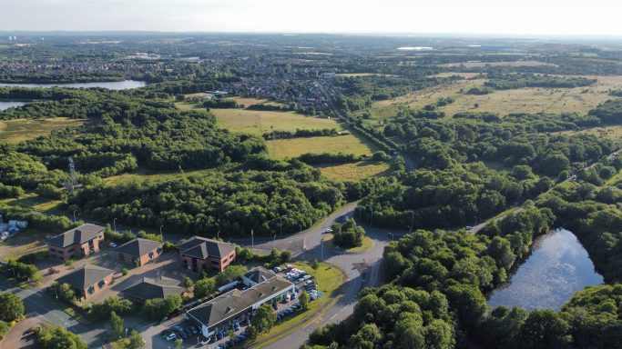 Aerial view of lush green fields, winding roads, and a tranquil lake.