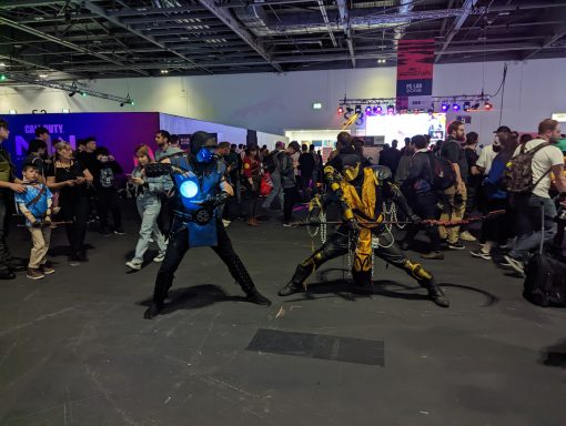 Two cosplayers dressed as superheroes in a crowded convention hall.